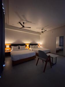 索姆纳特Hotel Madhukta Inn的有两张床和一把椅子的酒店房间