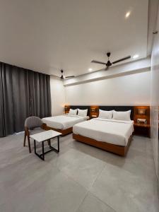 索姆纳特Hotel Madhukta Inn的有两张床和一张桌子的酒店房间