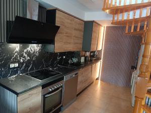 a kitchen with wooden cabinets and a stove top oven at ATICO DELUXE JACUZZI La Cala BENIDORM in Benidorm