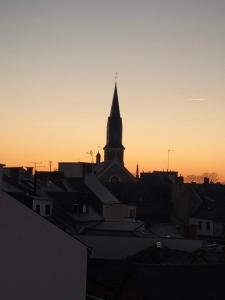 a silhouette of a church with a steeple at sunset at Le Familia in Guer