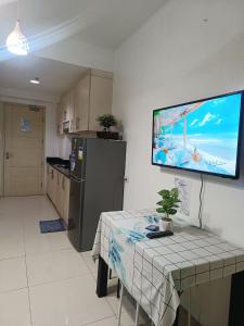 Il comprend une cuisine avec une table et une télévision murale. dans l'établissement Amigo's Place at Sea Residences, à Manille