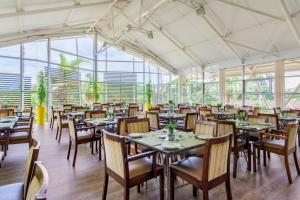 a dining room with tables and chairs and windows at Protea Hotel by Marriott Karridene Beach in Amanzimtoti