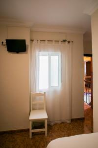 a white chair sitting in front of a window at Pensión Dulces Sueños in Seville +100 photos