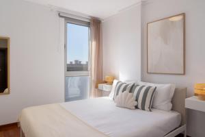 een witte slaapkamer met een bed en een raam bij Wings Apartment II by An Island Apart in Santa Cruz