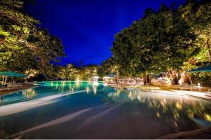 a swimming pool at night with trees and chairs at Tambuli Seaside Living Condominium -Private Host Tower D in Maribago