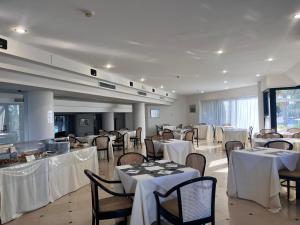 a restaurant with tables and chairs with white table cloth at Hyencos Hotel Calos in Torre San Giovanni Ugento