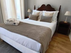 a bedroom with a large white bed with two lamps at Mourisca 1810 Guest House in Águeda