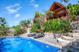 a swimming pool in front of a house at Adinata Villa by Manara in Seraya