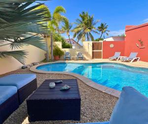 a swimming pool with a table and chairs next to it at Bubali Gardens - Eagle Beach's Oasis in Noord