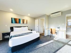 a bedroom with a large white bed and a desk at Camelot On Ulster in Hamilton +37 photos