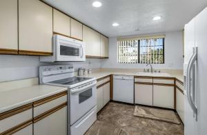 a kitchen with white appliances and wooden cabinets at Stylish Condo with Private Pool & & Panoramic View in Palm Springs