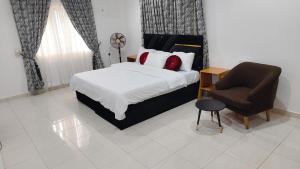a bedroom with a bed and a chair at Keev Homes 2 bedroom Apartment in Port Harcourt