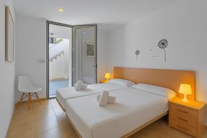 a bedroom with two beds and a table and a chair at Chalet Molins 5 By home villas 360 in Cala de Sant Vicent +25 photos