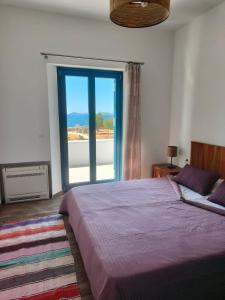 a bedroom with a bed and a large window at Kedros in Lipsoi