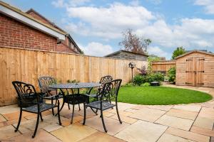 un patio avec une table et des chaises et une clôture dans l'établissement Cherry Tree Cottage, à Bicester