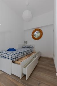 a white bedroom with a bed and a clock on the wall at Green Terrace in Cernobbio center in Cernobbio