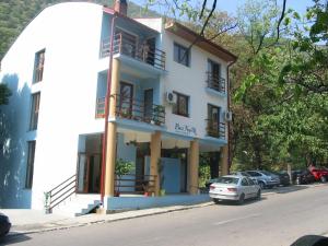a white building with cars parked in front of it at Pinul Negru in Băile Herculane