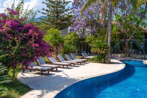 a row of lounge chairs next to a pool with purple flowers at Cottage House - Adult Only in Antalya +37 photos
