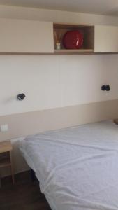 a bedroom with a white bed and a red plate on a shelf at Camping le lac des rêves Mobil home "Séléna" possibilité location trottinette Electrique in Lattes +14 photos