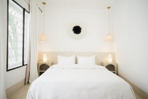 a white bedroom with a white bed and two lamps at Riad Dar Mimi in Marrakech