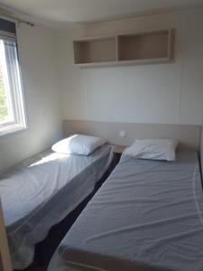 two beds sitting next to each other in a room at Camping le lac des rêves Mobil home "Séléna" possibilité location trottinette Electrique in Lattes