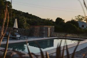 a swimming pool with a bench and a umbrella at Sea You Soon & Spa 1 in Methana