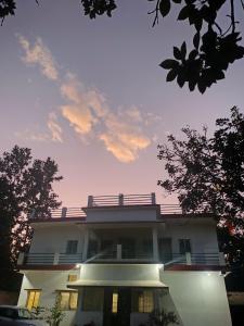 un grande edificio bianco con alberi di fronte di Aparajita Home Stay a Hesālong