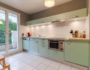 セリにあるCosy Appartement - Val d'Europe - Vallée Shopping - Disneyの青いキャビネットと窓付きの広いキッチン