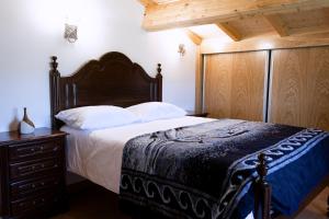 ein Schlafzimmer mit einem großen Bett mit einem hölzernen Kopfteil in der Unterkunft Casa da Ladeira in Videmonte