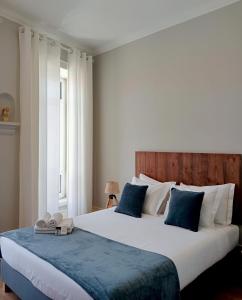 a bedroom with a large bed with blue and white pillows at Mourisca 1810 Guest House in Águeda