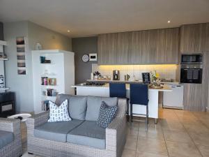 a living room with a couch and a kitchen at Amelia's by the Sea in Groot Brak Rivier