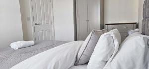 een wit bed met witte lakens en kussens bij Spacious Luxurious Serviced Accommodation 7 in Preston