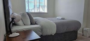 een slaapkamer met een bed met witte lakens en een lamp bij Spacious Luxurious Serviced Accommodation 7 in Preston