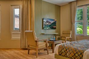 a hotel room with a bed and a desk and chairs at Mountain Nest A Boutique Stay Near Dal Lake, Srinagar in Srinagar