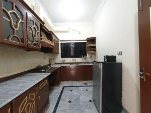 a kitchen with wooden cabinets and a black refrigerator at ROOM Cozy Guest Room in Rawalpindi - Perfect FAMILY ONLY in Rawalpindi +48 photos