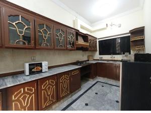 a kitchen with wooden cabinets and a microwave at ROOM Cozy Guest Room in Rawalpindi - Perfect FAMILY ONLY in Rawalpindi