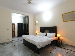 a bedroom with a bed with white sheets and two lamps at ROOM Cozy Guest Room in Rawalpindi - Perfect FAMILY ONLY in Rawalpindi