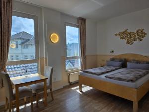 a bedroom with a bed and a table and windows at Hotel Deichvoigt in Cuxhaven +276 photos