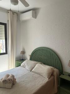 Una cama con cabecero verde en un dormitorio. en TropicanaB11, en Nerja