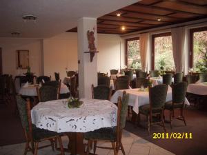 un comedor con mesas y sillas blancas y ventanas en Landhotel Pingel, en Sundern