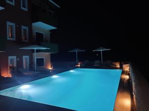 a swimming pool lit up at night with umbrellas at Porto Nirikos Lefkada in Lefkada