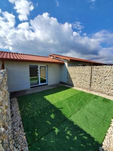 a house with a retaining wall and a green lawn at ARCADIA Village in Merei