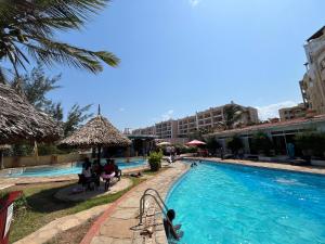 Una piscina en un hotel con gente sentada en Bahari bliss apartments, en Mombasa
