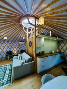 a room with a couch and a kitchen in a yurt at Szumi Brzoza in Osieczek Piwnice