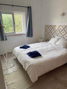 a bedroom with a bed with two blue towels on it at Quinta Madrugada Burgau in Luz