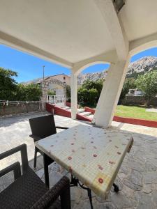a table and chairs on a patio with mountains in the background at Vila Tesmija in Baška