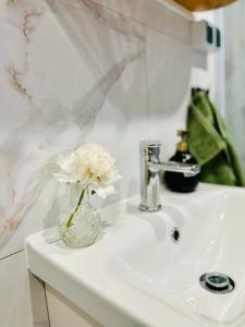 a vase with white flowers sitting on a bathroom sink at Szumi Brzoza in Osieczek Piwnice +96 photos