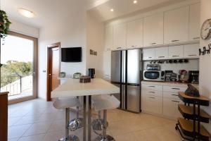 a kitchen with white cabinets and a stainless steel refrigerator at Villa Gentileschi in Casarano