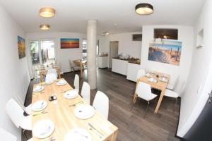 a dining room with a wooden table and white chairs at Schäfer Boardinghouse in Gröbenzell
