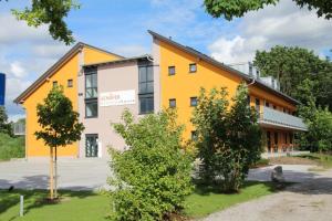 un edificio blanco y amarillo con árboles delante en Schäfer Boardinghouse, en Gröbenzell